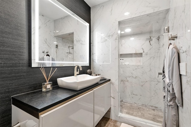 bathroom with vanity, a tile shower, backsplash, and tile walls