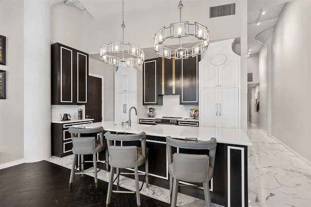 dining space with an inviting chandelier, sink, a towering ceiling, and dark hardwood / wood-style flooring