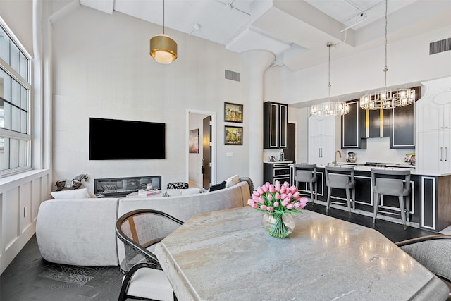 dining room featuring a high ceiling, sink, a notable chandelier, and dark hardwood / wood-style flooring