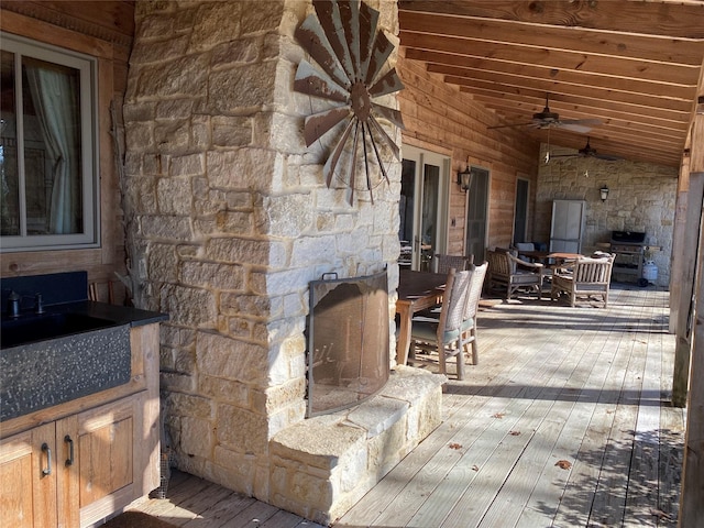 wooden deck featuring sink, exterior fireplace, and ceiling fan