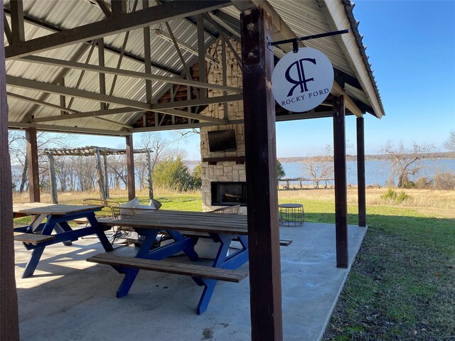 view of patio with an outdoor stone fireplace and a gazebo