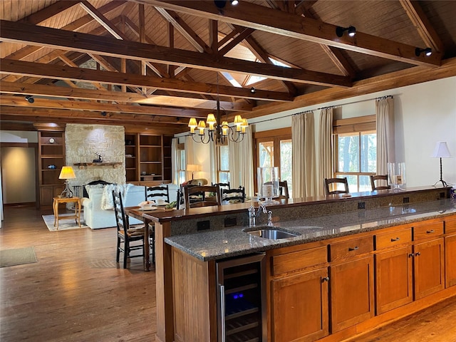 kitchen with a fireplace, sink, dark stone countertops, wine cooler, and light hardwood / wood-style floors