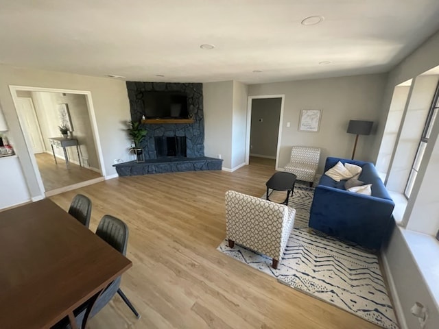 living room with hardwood / wood-style flooring and a stone fireplace