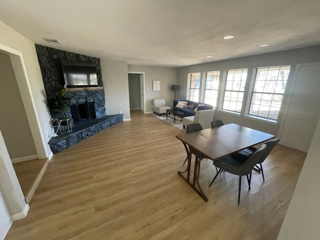 dining area featuring a stone fireplace and wood-type flooring