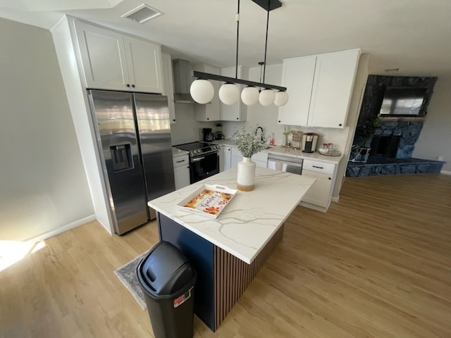 kitchen with decorative light fixtures, a center island, stainless steel appliances, and white cabinetry