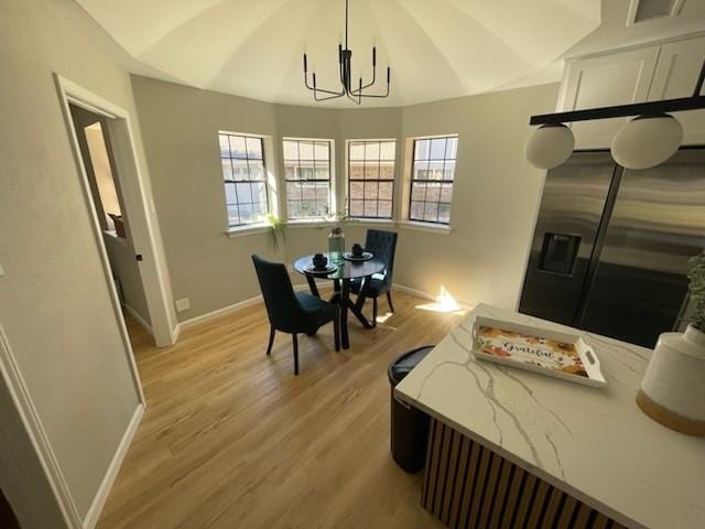 dining space with a chandelier, light hardwood / wood-style floors, and lofted ceiling