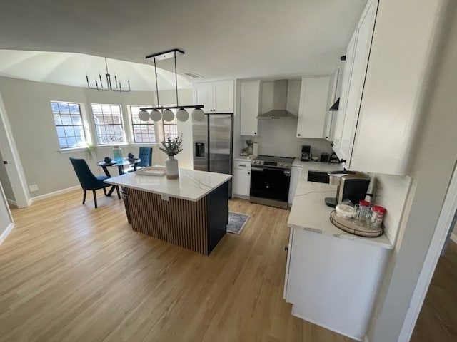 kitchen featuring white cabinetry, wall chimney exhaust hood, stainless steel appliances, decorative light fixtures, and a kitchen island