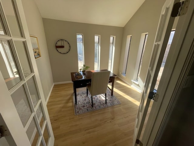 dining space with vaulted ceiling and light hardwood / wood-style flooring