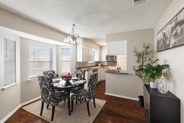 dining area featuring a chandelier, a textured ceiling, dark hardwood / wood-style flooring, and sink