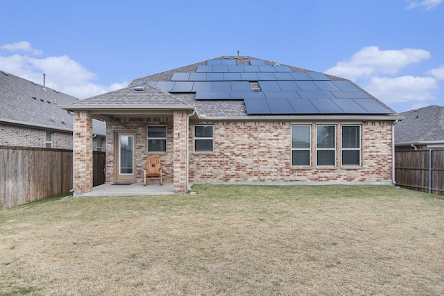 rear view of house featuring a lawn, a patio, and solar panels