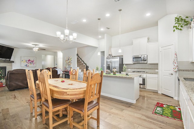 dining space with ceiling fan with notable chandelier and light hardwood / wood-style flooring