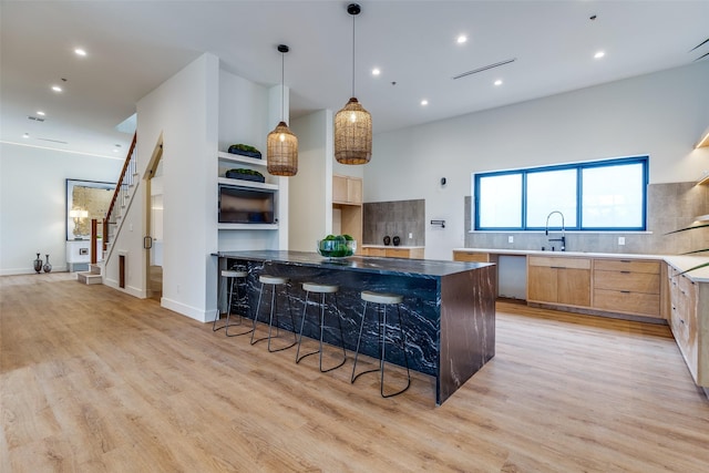 kitchen with tasteful backsplash, sink, pendant lighting, and light hardwood / wood-style floors