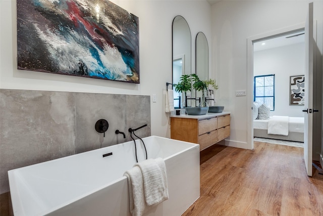 bathroom with hardwood / wood-style flooring, vanity, and a bath