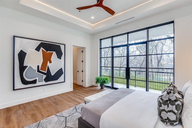 bedroom featuring a tray ceiling, ceiling fan, and light hardwood / wood-style flooring