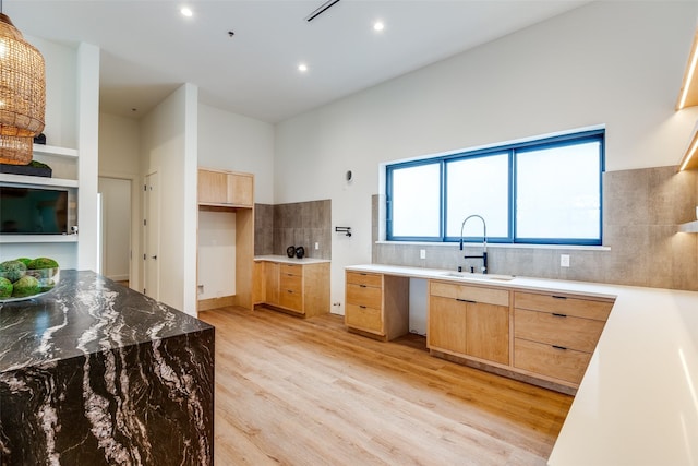 kitchen featuring sink, light brown cabinetry, light wood-type flooring, and decorative backsplash