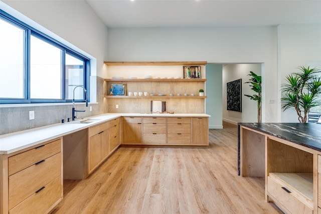 kitchen with tasteful backsplash, sink, light brown cabinetry, and light wood-type flooring