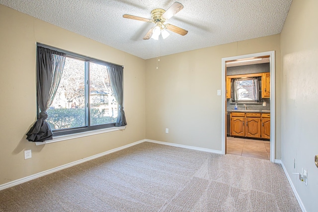 empty room with ceiling fan, sink, light colored carpet, and a textured ceiling