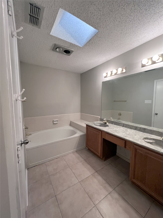 bathroom with a skylight, vanity, a washtub, tile patterned floors, and a textured ceiling