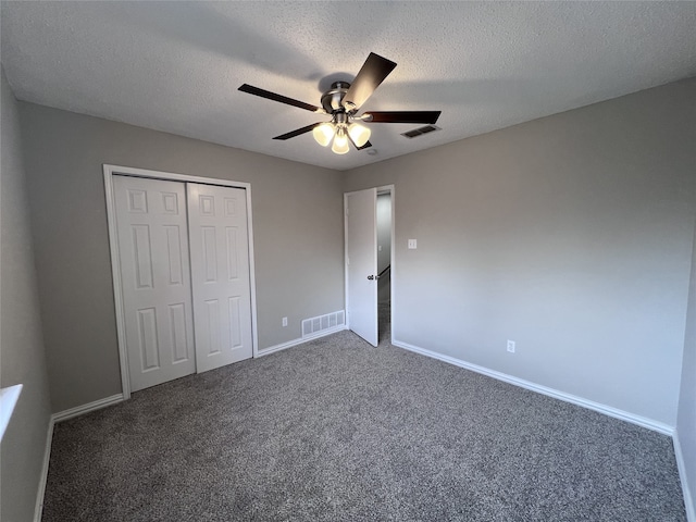 unfurnished bedroom with ceiling fan, dark carpet, a closet, and a textured ceiling