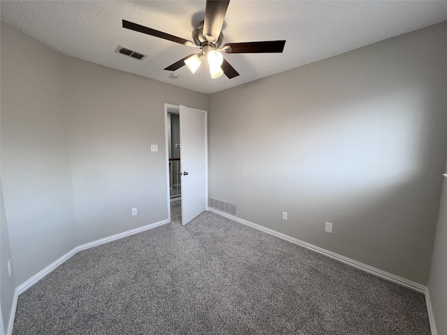 carpeted empty room featuring ceiling fan and a textured ceiling