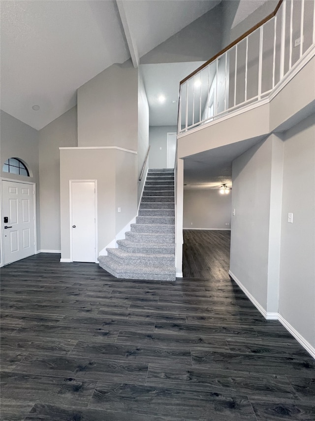 staircase featuring beamed ceiling, wood-type flooring, and high vaulted ceiling