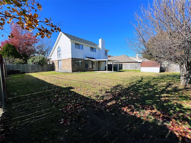 rear view of house with a yard, a patio area, and a storage shed