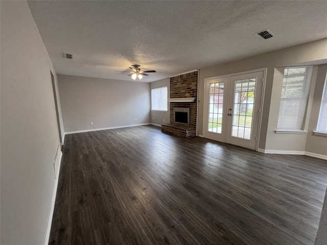 unfurnished living room with ceiling fan, a textured ceiling, a fireplace, and dark hardwood / wood-style flooring