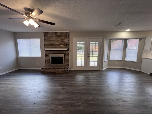 unfurnished living room with a wealth of natural light, a fireplace, dark hardwood / wood-style floors, and a textured ceiling