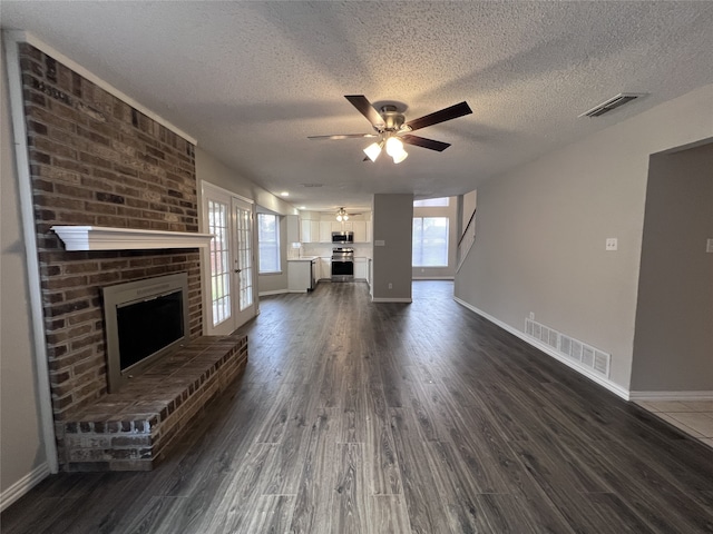 unfurnished living room with ceiling fan, dark hardwood / wood-style flooring, a fireplace, and a textured ceiling