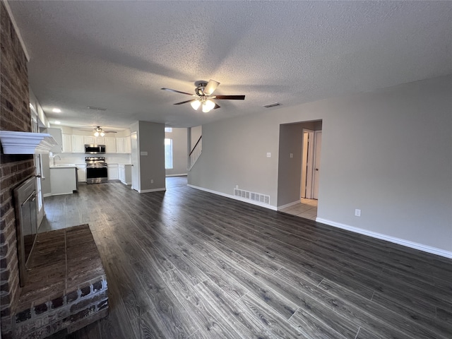 unfurnished living room featuring sink, a brick fireplace, a textured ceiling, dark hardwood / wood-style flooring, and ceiling fan