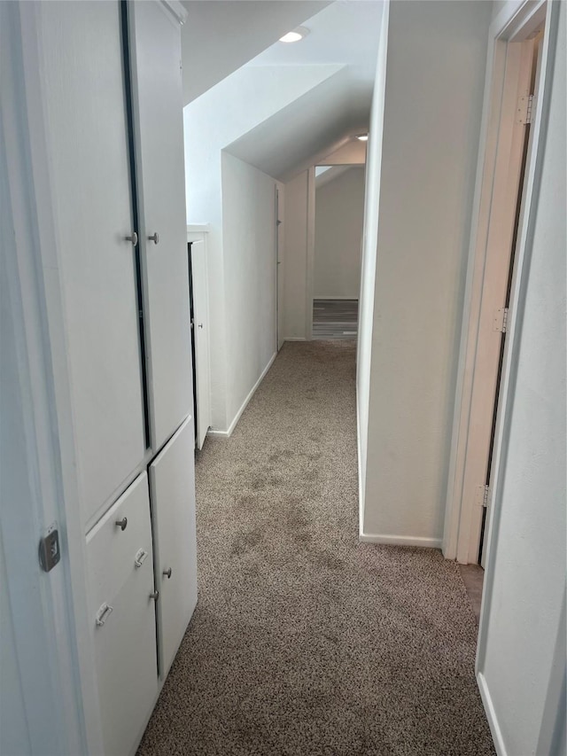 hallway featuring lofted ceiling and light carpet