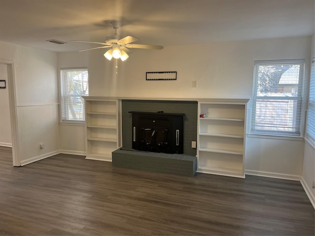 unfurnished living room with a brick fireplace, ceiling fan, and dark wood-type flooring