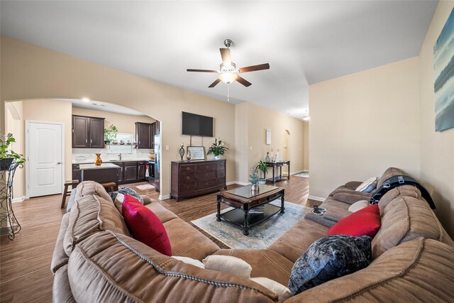 living room featuring ceiling fan, sink, and light hardwood / wood-style floors