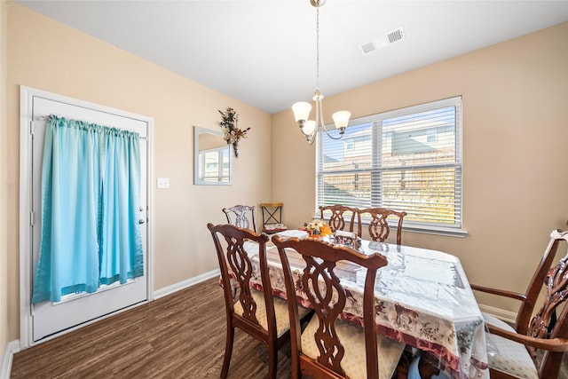 dining space with dark hardwood / wood-style floors and a chandelier