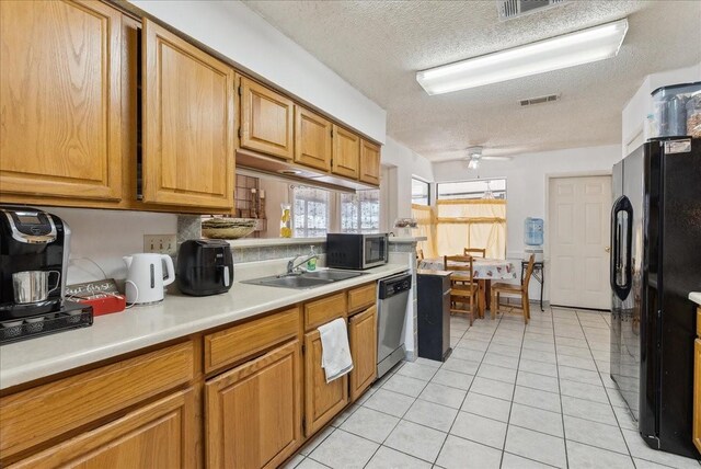 kitchen with dishwasher, black refrigerator, sink, ceiling fan, and a textured ceiling