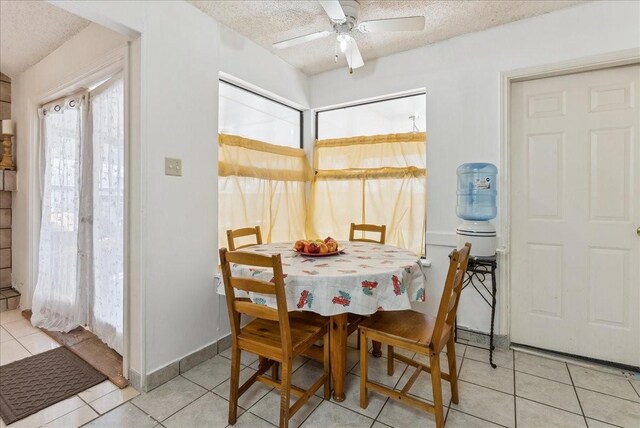 tiled dining space with a textured ceiling and ceiling fan