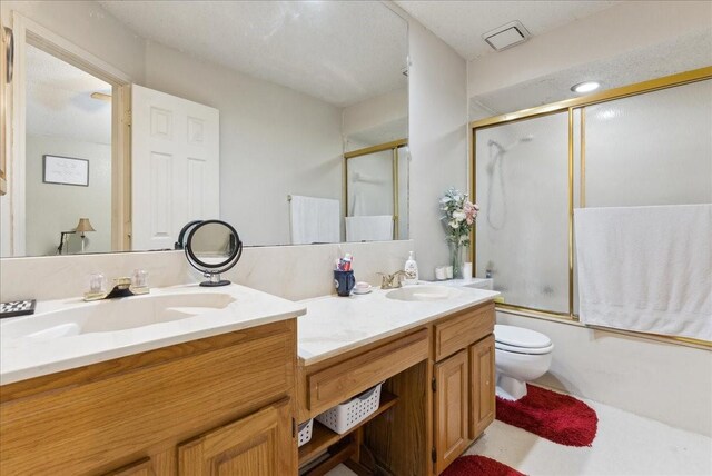 full bathroom featuring shower / bath combination with glass door, vanity, and toilet