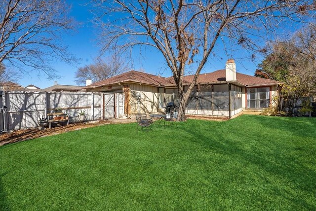 rear view of property featuring a yard and a sunroom