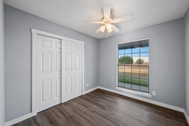 unfurnished bedroom featuring ceiling fan, dark wood-type flooring, and a closet