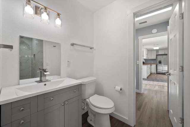 bathroom with a shower, hardwood / wood-style floors, vanity, and toilet