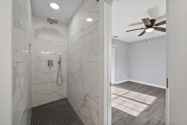 bathroom with a tile shower, ceiling fan, and wood-type flooring