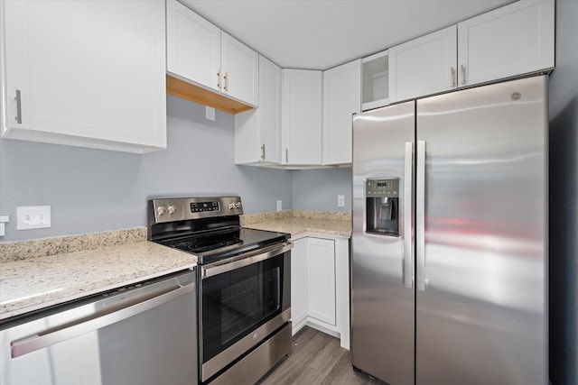 kitchen with white cabinets, dark hardwood / wood-style floors, light stone counters, and stainless steel appliances