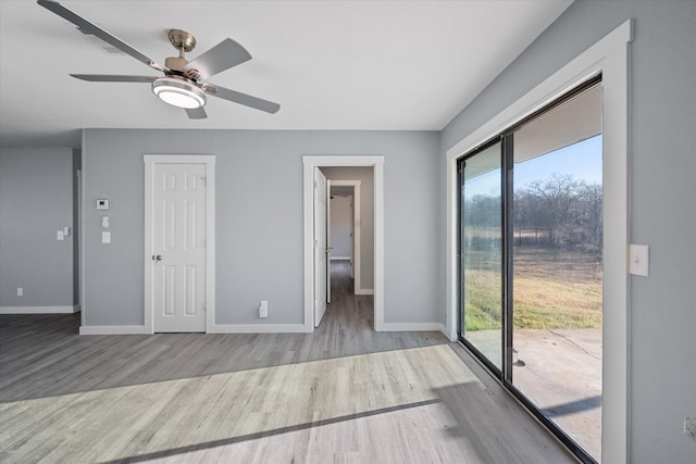 empty room with ceiling fan, a wealth of natural light, and light hardwood / wood-style flooring