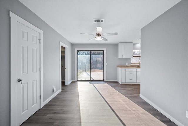 interior space with white cabinets, ceiling fan, and dark wood-type flooring