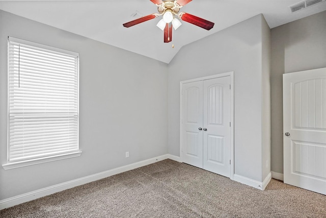 unfurnished bedroom with ceiling fan, a closet, light colored carpet, and vaulted ceiling