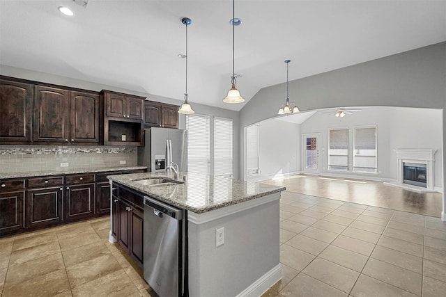 kitchen with ceiling fan, stainless steel appliances, backsplash, vaulted ceiling, and a center island with sink