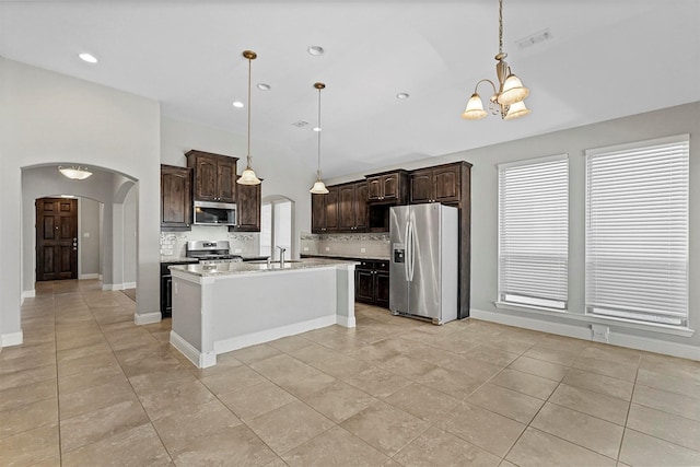 kitchen with a center island with sink, dark brown cabinets, decorative light fixtures, and appliances with stainless steel finishes