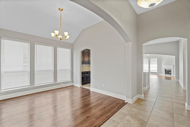 interior space with light tile patterned floors, vaulted ceiling, and a notable chandelier