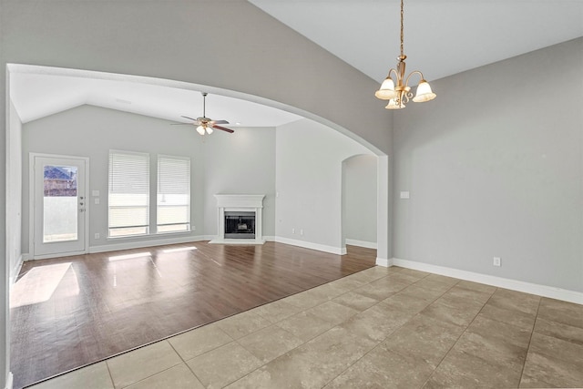 unfurnished living room featuring ceiling fan with notable chandelier, vaulted ceiling, and light tile patterned flooring