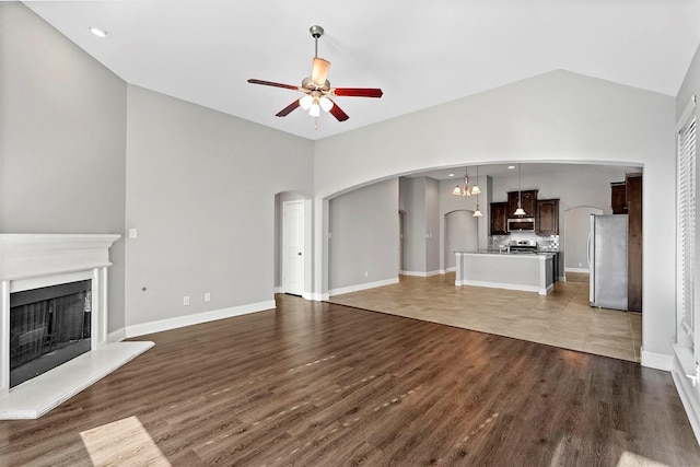 unfurnished living room with ceiling fan, high vaulted ceiling, and wood-type flooring